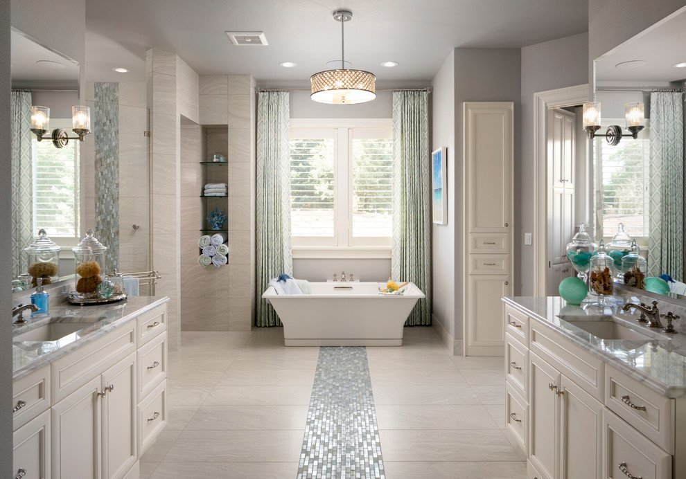 Bild på ett stort vintage vit vitt en-suite badrum, med luckor med infälld panel, vita skåp, ett fristående badkar, en kantlös dusch, grå kakel, porslinskakel, grå väggar, klinkergolv i porslin, ett undermonterad handfat, marmorbänkskiva, flerfärgat golv och med dusch som är öppen