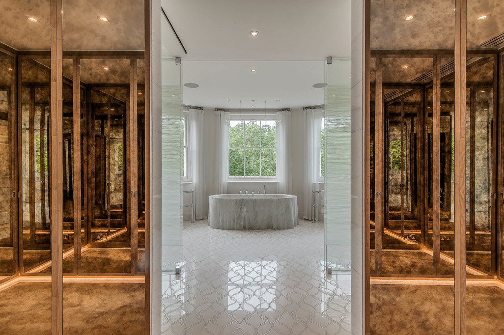 Expansive traditional shower room bathroom in London with glass-front cabinets, black cabinets, a freestanding bath, a walk-in shower, a one-piece toilet, white tiles, stone slabs, white walls, marble flooring, a built-in sink and marble worktops.