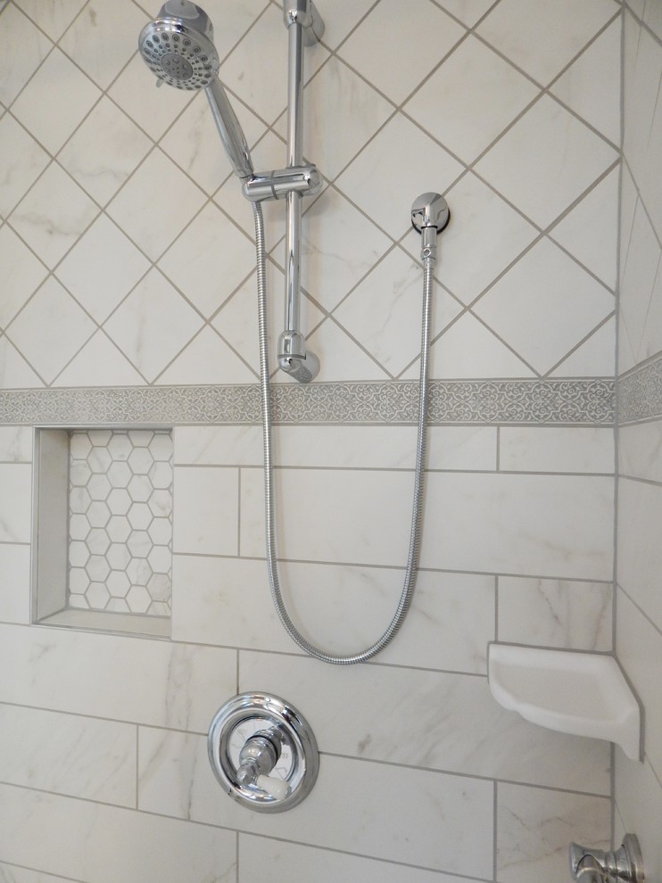 Inredning av ett klassiskt badrum, med skåp i shakerstil, vita skåp, en hörndusch, vit kakel, porslinskakel, grå väggar, klinkergolv i porslin, ett undermonterad handfat och marmorbänkskiva