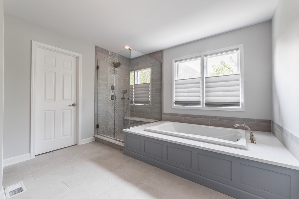 Inspiration for a large transitional master gray tile and ceramic tile ceramic tile and gray floor bathroom remodel in Chicago with recessed-panel cabinets, gray cabinets, gray walls, an undermount sink, quartzite countertops, a hinged shower door and white countertops
