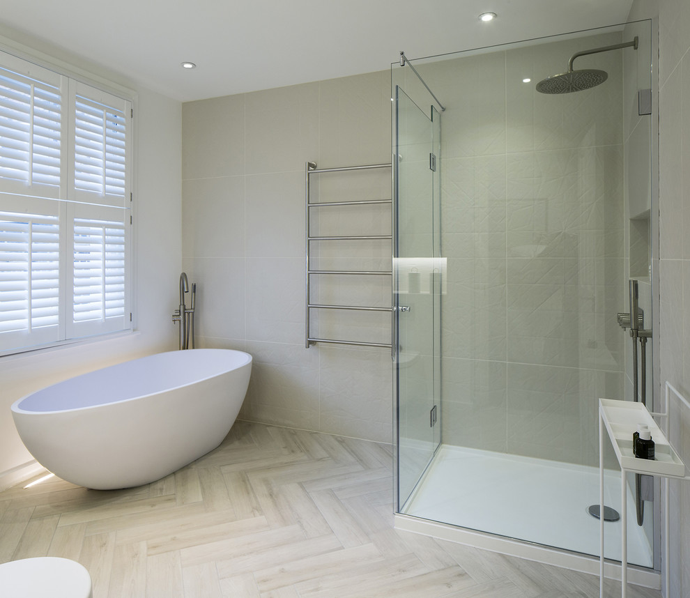 Design ideas for a large contemporary family bathroom in London with flat-panel cabinets, white cabinets, a freestanding bath, a corner shower, a wall mounted toilet, beige tiles, porcelain tiles, beige walls, porcelain flooring, a built-in sink and solid surface worktops.