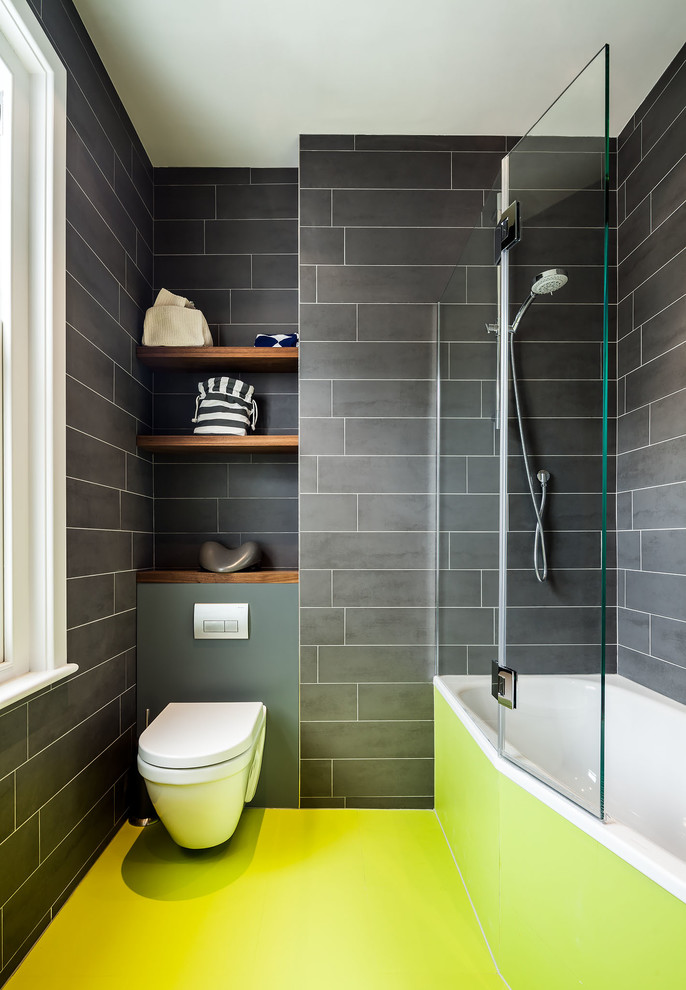 Réalisation d'une salle de bain design avec une baignoire posée, un combiné douche/baignoire, WC suspendus et un sol vert.