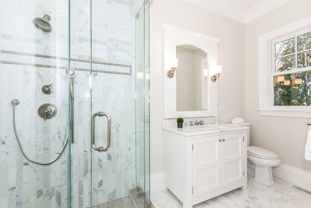 Diseño de cuarto de baño clásico con lavabo bajoencimera, puertas de armario blancas y baldosas y/o azulejos blancos
