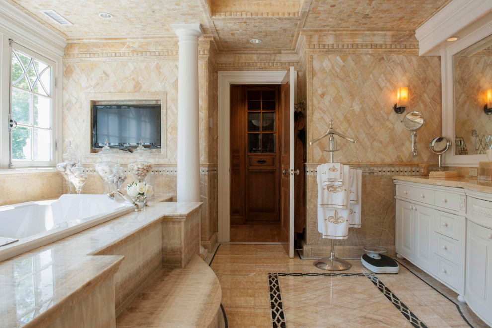 Aménagement d'une salle de bain principale classique avec un placard avec porte à panneau surélevé, des portes de placard blanches, une baignoire posée, un carrelage beige, un sol beige et un plan de toilette beige.
