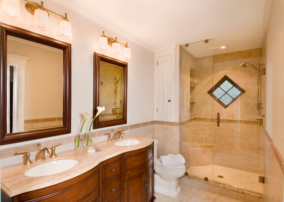ボストンにあるトラディショナルスタイルのおしゃれな浴室 (アンダーカウンター洗面器、中間色木目調キャビネット、アルコーブ型シャワー、ベージュのタイル、分離型トイレ、白い壁、セラミックタイルの床、開き戸のシャワー、落し込みパネル扉のキャビネット) の写真