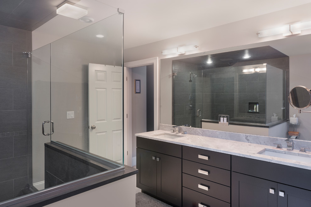 Exemple d'une grande salle de bain chic avec un placard à porte shaker, des portes de placard grises, une douche d'angle, un carrelage gris, des carreaux de porcelaine, un mur gris, un lavabo encastré, un plan de toilette en marbre et une cabine de douche à porte battante.