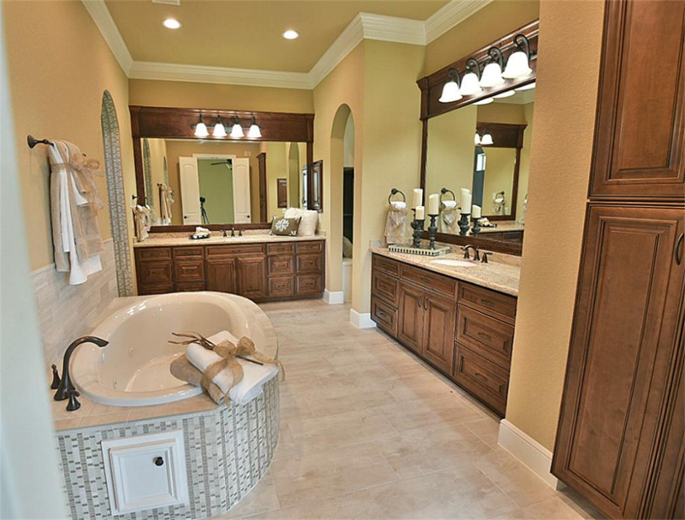 Idées déco pour une grande salle de bain principale classique avec un placard avec porte à panneau surélevé, des portes de placard marrons, un plan de toilette en granite, un plan de toilette beige, meuble double vasque et meuble-lavabo encastré.
