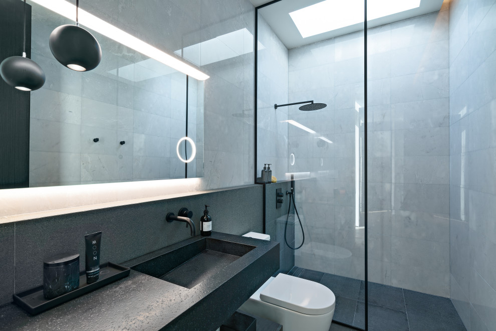 Example of a mid-century modern kids' gray tile and ceramic tile cement tile floor and black floor bathroom design in Miami with a two-piece toilet, gray walls, an integrated sink, onyx countertops and black countertops