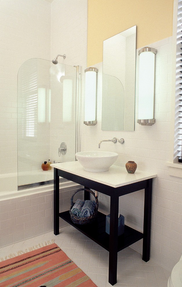 На фото: маленькая ванная комната в стиле модернизм с фасадами островного типа, темными деревянными фасадами, накладной ванной, душем над ванной, унитазом-моноблоком, белой плиткой, керамической плиткой, желтыми стенами, полом из керамической плитки, настольной раковиной, столешницей из искусственного кварца, душевой кабиной, серым полом, душем с распашными дверями и белой столешницей для на участке и в саду с
