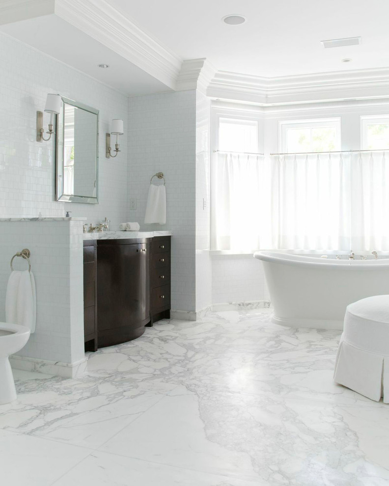 Foto de cuarto de baño principal tradicional grande con puertas de armario de madera en tonos medios, bañera exenta, baldosas y/o azulejos blancos, paredes blancas, suelo de mármol y suelo blanco
