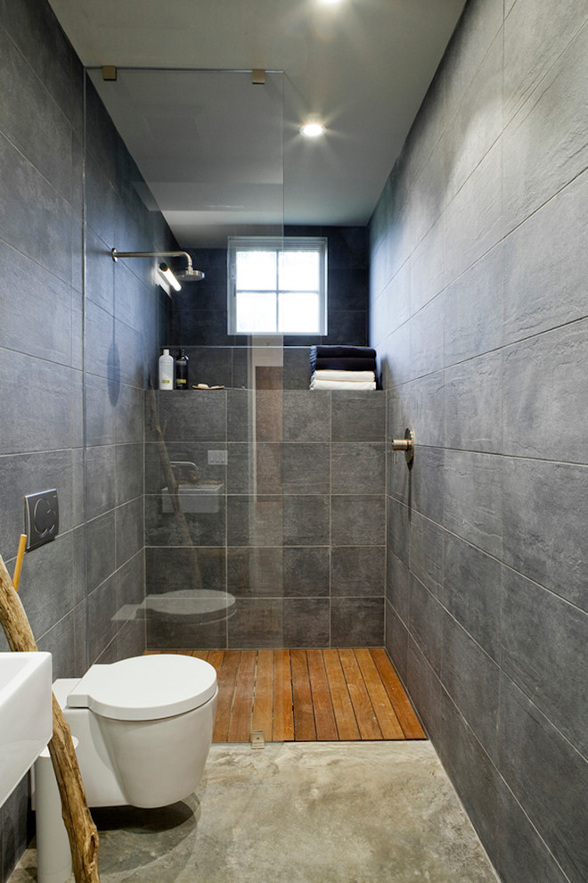 Foto de cuarto de baño largo y estrecho actual con ducha a ras de suelo, baldosas y/o azulejos grises, paredes grises y aseo y ducha