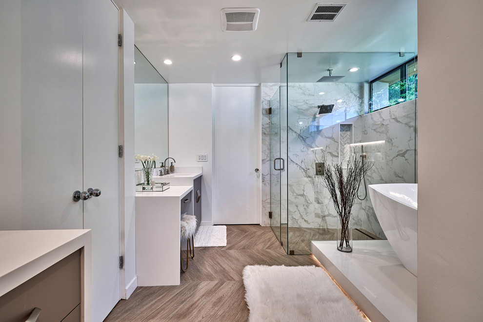 ロサンゼルスにあるコンテンポラリースタイルのおしゃれなマスターバスルーム (フラットパネル扉のキャビネット、茶色いキャビネット、置き型浴槽、バリアフリー、白いタイル、白い壁、アンダーカウンター洗面器、茶色い床、開き戸のシャワー、白い洗面カウンター) の写真