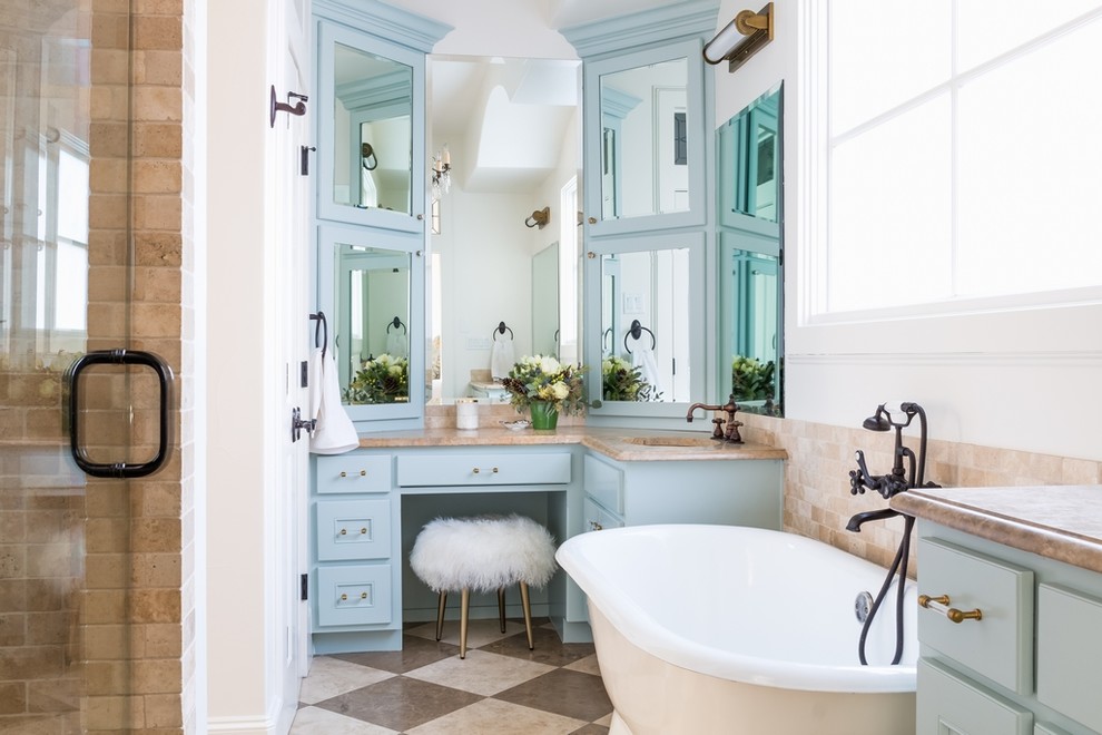 Modelo de cuarto de baño clásico renovado con armarios con paneles empotrados, puertas de armario azules, bañera exenta, baldosas y/o azulejos marrones, paredes blancas, suelo marrón y encimeras marrones