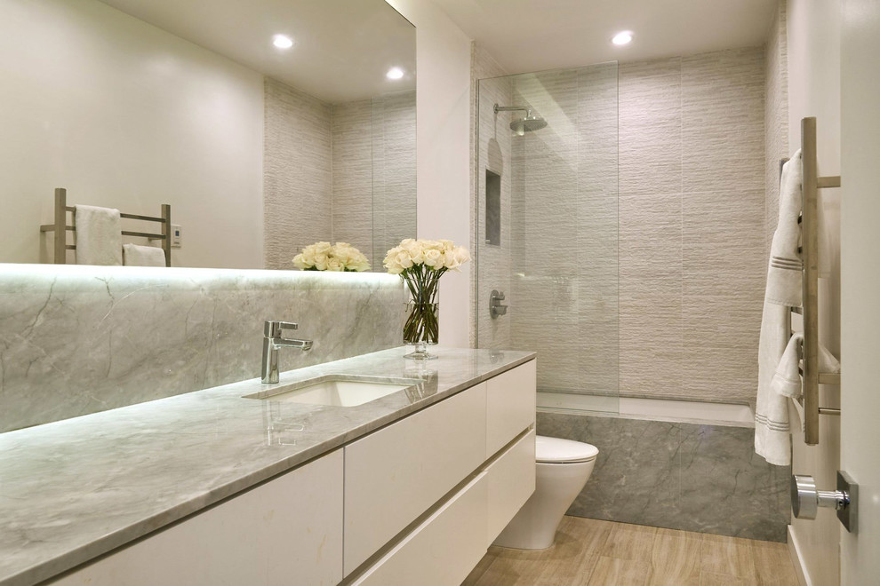 Пример оригинального дизайна: маленькая главная ванная комната в современном стиле с плоскими фасадами, белыми фасадами, полновстраиваемой ванной, душем над ванной, унитазом-моноблоком, бежевой плиткой, керамогранитной плиткой, белыми стенами, полом из керамогранита, врезной раковиной, мраморной столешницей, открытым душем и коричневым полом для на участке и в саду