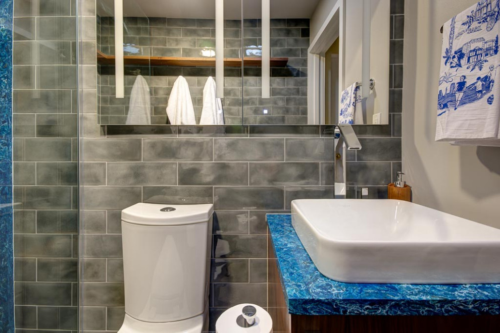 Diseño de cuarto de baño ecléctico pequeño con puertas de armario de madera oscura, ducha a ras de suelo, baldosas y/o azulejos grises, paredes grises, aseo y ducha, suelo gris, ducha abierta y encimeras azules