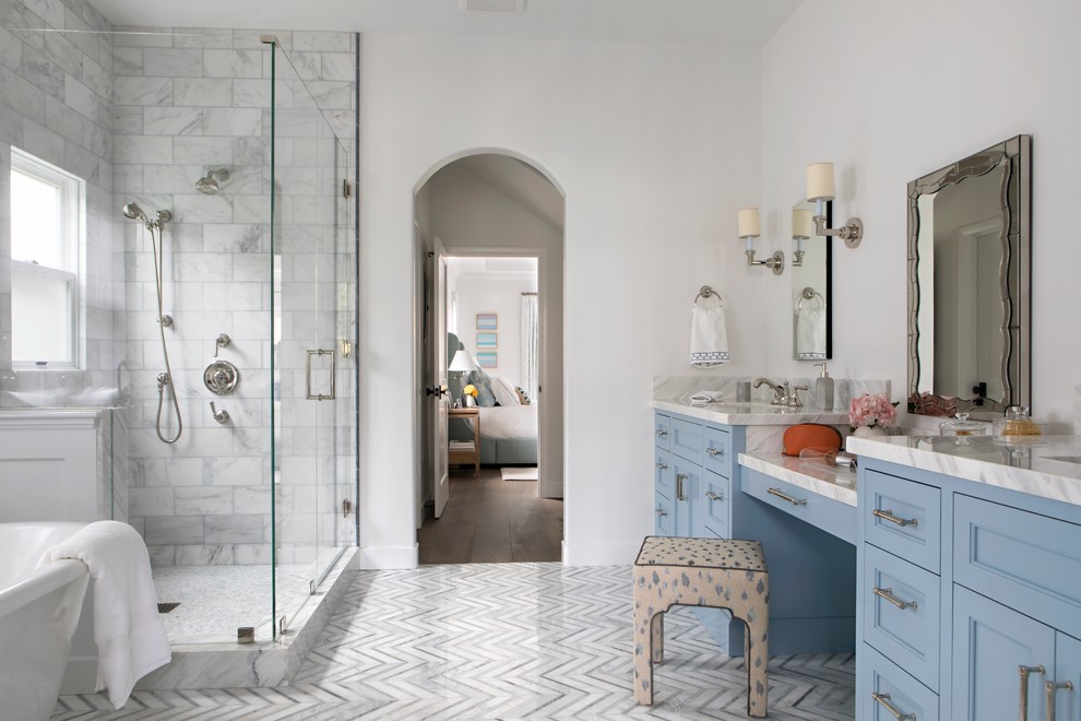 Inspiration for a large transitional master marble tile and white tile marble floor and gray floor bathroom remodel in Los Angeles with blue cabinets, a one-piece toilet, white walls, an undermount sink, marble countertops, a hinged shower door, recessed-panel cabinets and white countertops