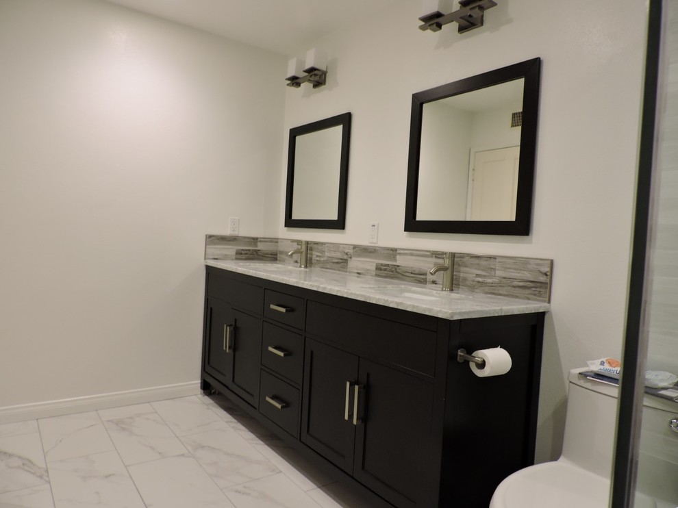 Идея дизайна: большая главная ванная комната в стиле неоклассика (современная классика) с фасадами в стиле шейкер, черными фасадами, душем в нише, раздельным унитазом, серой плиткой, керамогранитной плиткой, белыми стенами, мраморным полом, врезной раковиной, мраморной столешницей, белым полом и душем с распашными дверями