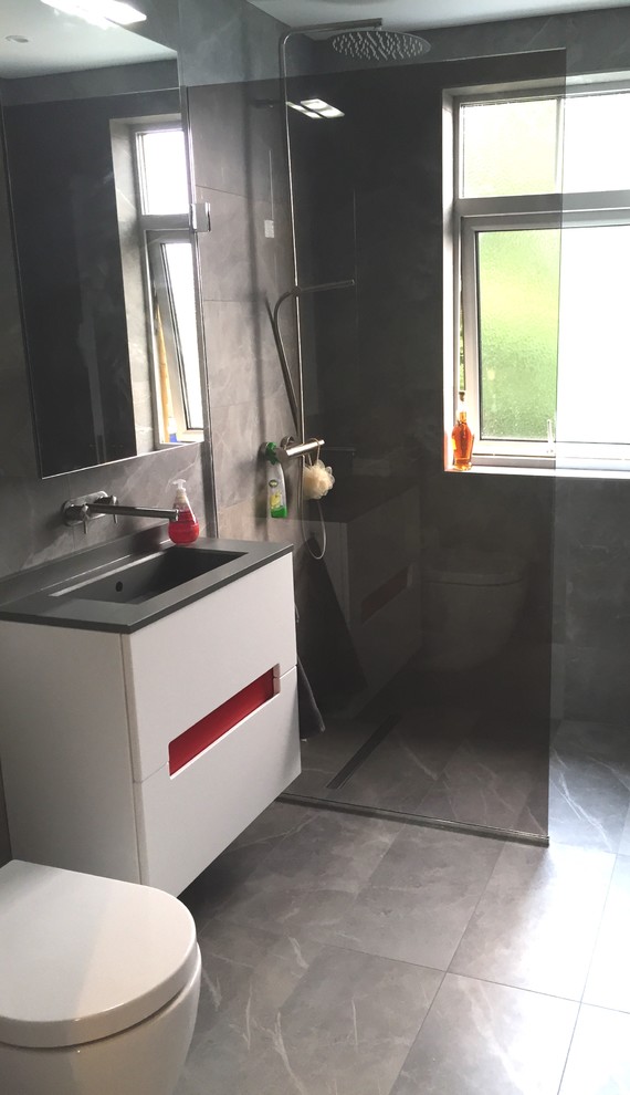 Modelo de cuarto de baño actual pequeño con ducha abierta, sanitario de una pieza, baldosas y/o azulejos grises, suelo de baldosas de porcelana y aseo y ducha