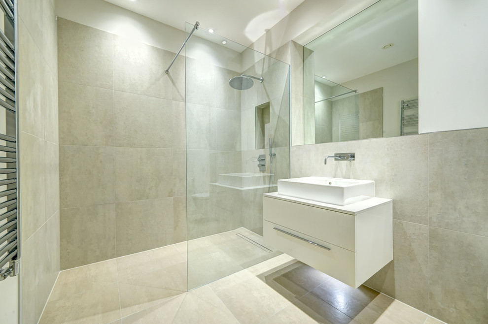 Inredning av ett modernt stort en-suite badrum, med ett avlångt handfat, släta luckor, vita skåp, en öppen dusch, en vägghängd toalettstol, flerfärgad kakel, porslinskakel, grå väggar och klinkergolv i porslin