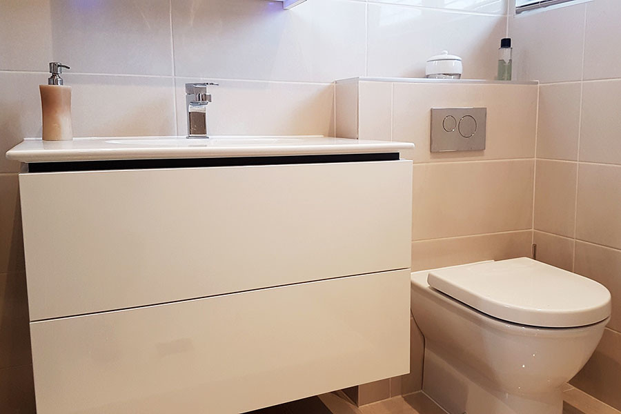 Small modern shower room bathroom in Dorset with a wall mounted toilet, beige walls and a hinged door.