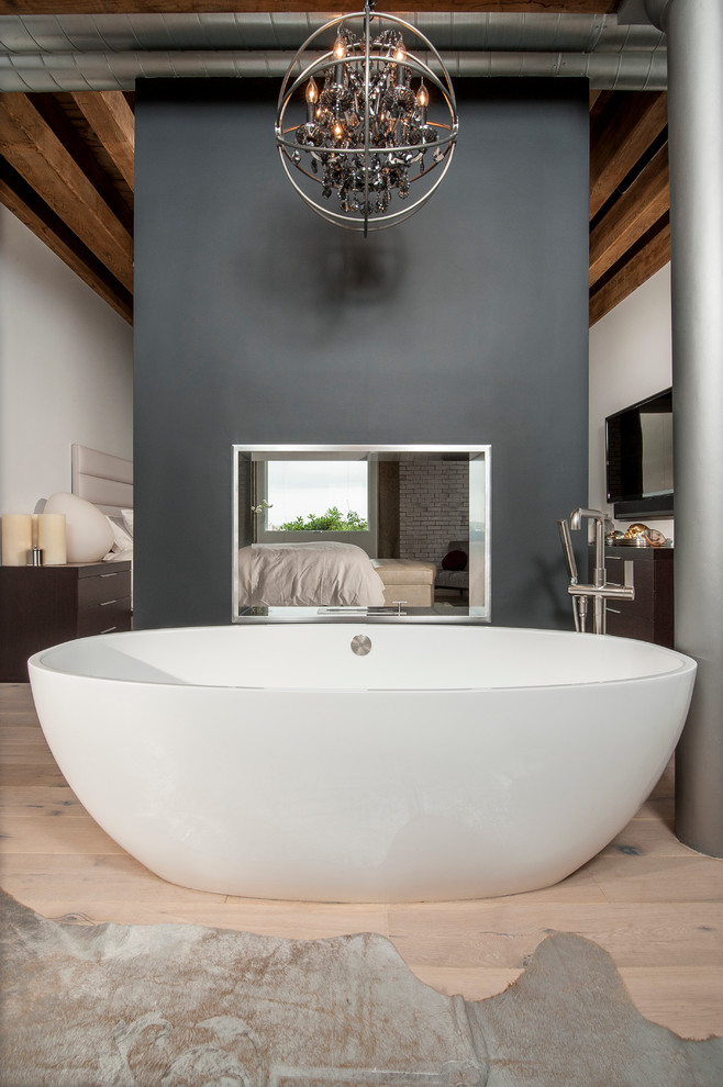 Foto di una stanza da bagno padronale industriale di medie dimensioni con vasca freestanding, doccia alcova e parquet chiaro