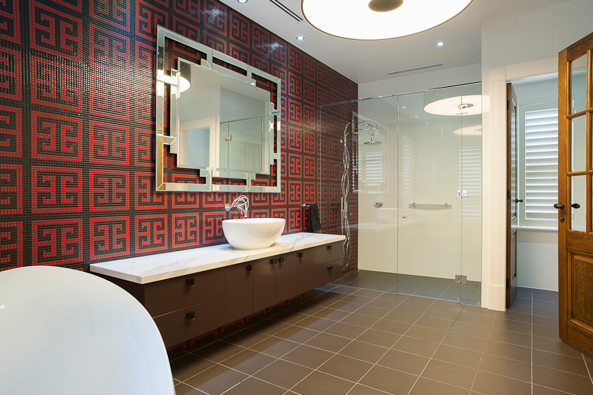 Asiatisk inredning av ett en-suite badrum, med ett fristående handfat, möbel-liknande, bruna skåp, marmorbänkskiva, ett fristående badkar, en öppen dusch, en vägghängd toalettstol, svart kakel, vita väggar och klinkergolv i porslin