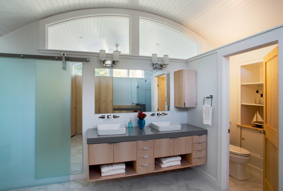 Ejemplo de cuarto de baño actual con armarios con paneles lisos, puertas de armario de madera clara y encimera de cuarzo compacto