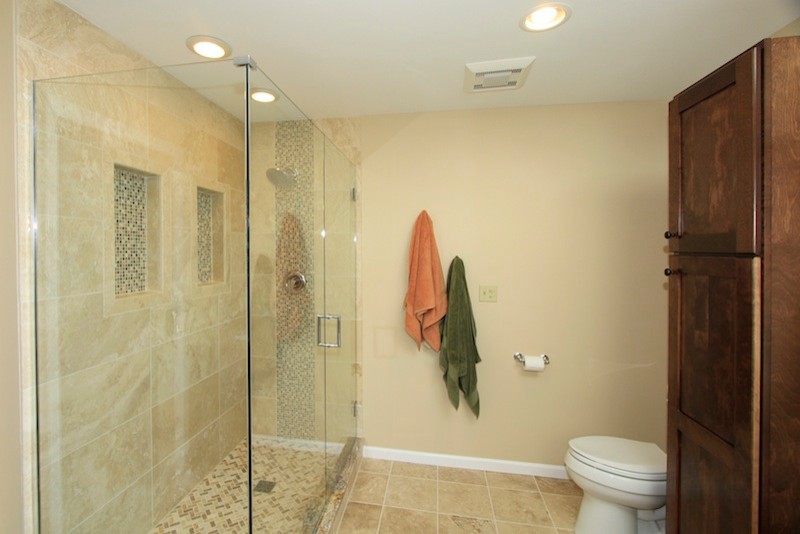 Photo of a traditional ensuite bathroom in Chicago with a submerged sink, recessed-panel cabinets, medium wood cabinets, granite worktops, a built-in bath, a corner shower, a two-piece toilet, beige tiles, stone tiles, beige walls and travertine flooring.