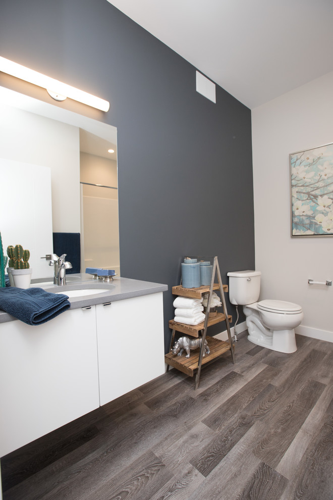 Inredning av ett modernt stort en-suite badrum, med släta luckor, vita skåp, ett badkar i en alkov, en dusch i en alkov, en toalettstol med hel cisternkåpa, blå väggar, mellanmörkt trägolv, ett undermonterad handfat, bänkskiva i akrylsten, brunt golv och dusch med duschdraperi
