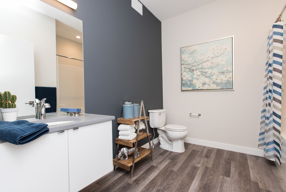 Bathroom - large modern master medium tone wood floor and brown floor bathroom idea in Other with flat-panel cabinets, white cabinets, a one-piece toilet, blue walls, an undermount sink and solid surface countertops