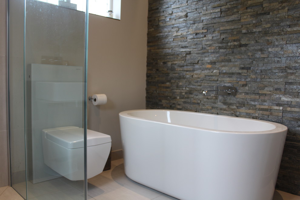 Example of a mid-sized trendy kids' brown tile and stone tile porcelain tile bathroom design in Other with glass-front cabinets, gray cabinets, a wall-mount toilet, white walls and a console sink