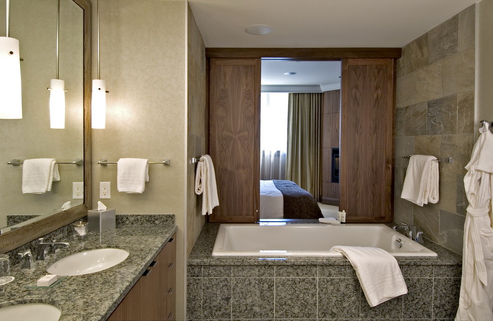 This is an example of a contemporary bathroom in Vancouver with a submerged sink, flat-panel cabinets, medium wood cabinets, a built-in bath and grey tiles.