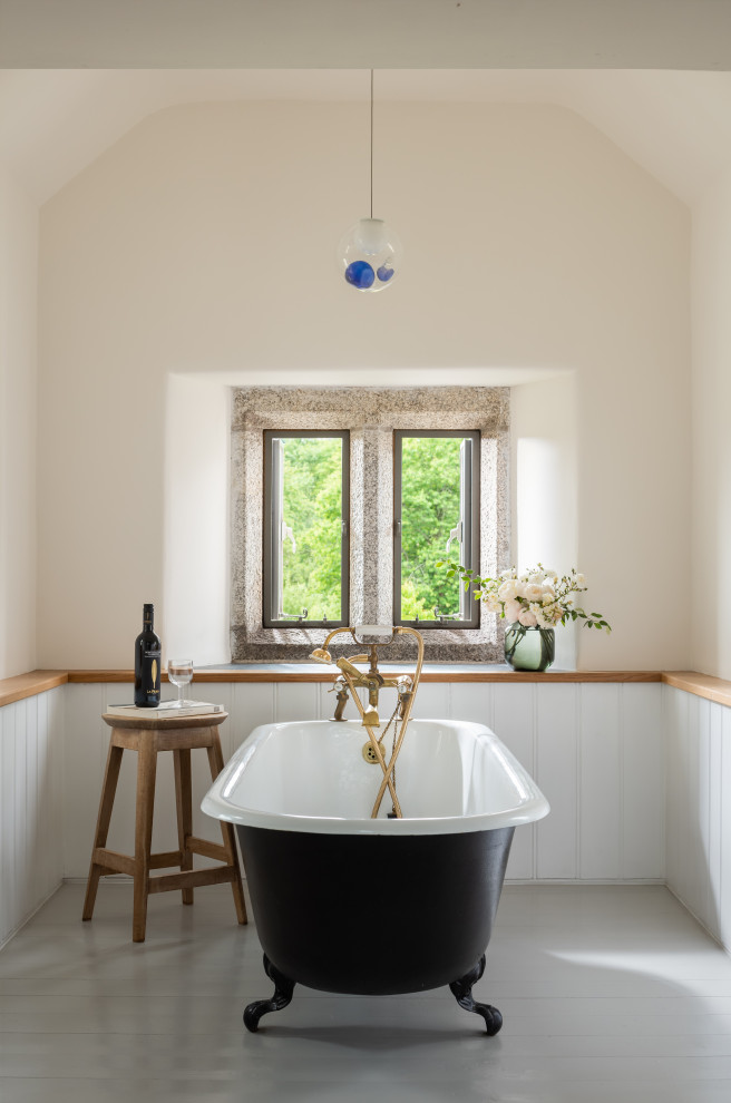 Exempel på ett klassiskt badrum, med ett badkar med tassar, målat trägolv och vitt golv