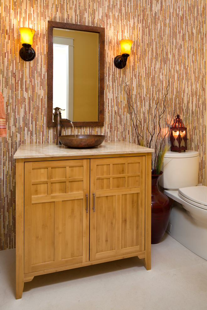Стильный дизайн: маленькая ванная комната в восточном стиле с настольной раковиной, фасадами островного типа, светлыми деревянными фасадами, столешницей из известняка, унитазом-моноблоком, разноцветной плиткой, каменной плиткой, желтыми стенами, полом из известняка и душевой кабиной для на участке и в саду - последний тренд