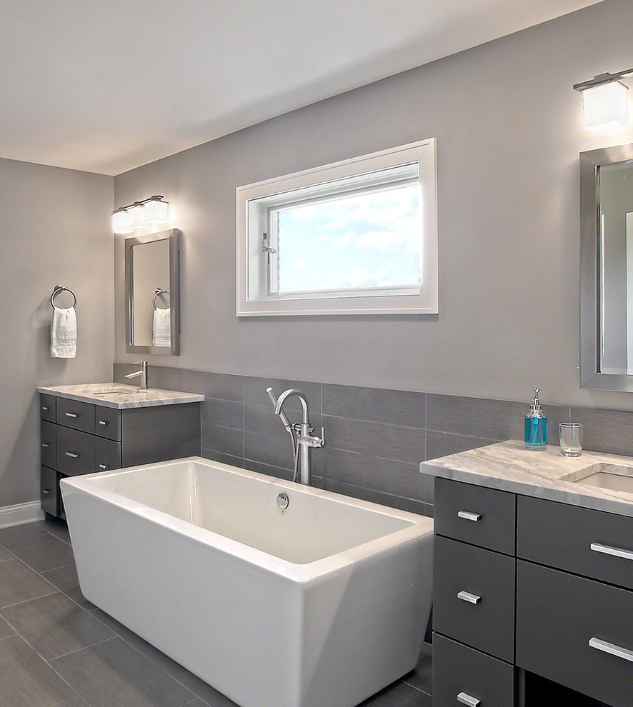Exempel på ett mellanstort modernt en-suite badrum, med släta luckor, grå skåp, ett fristående badkar, grå kakel, keramikplattor, grå väggar, klinkergolv i keramik, ett undermonterad handfat och marmorbänkskiva