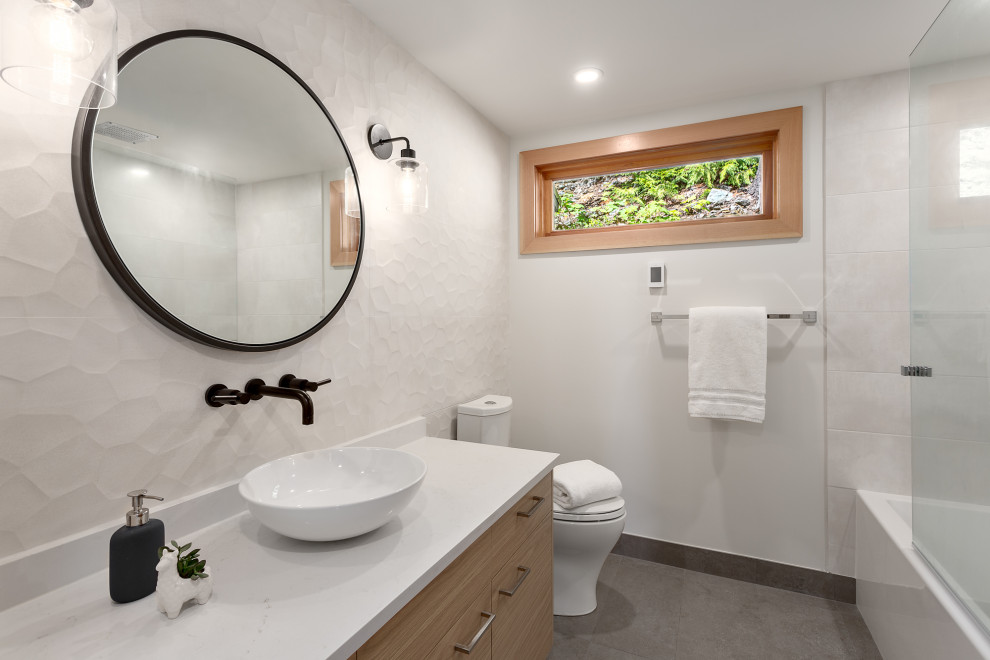 Aménagement d'une salle de bain contemporaine en bois brun avec un placard à porte plane, un carrelage blanc, une vasque, un sol gris et un plan de toilette blanc.
