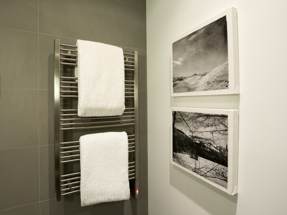 Cette photo montre une salle de bain moderne en bois brun de taille moyenne avec un placard à porte plane, une douche à l'italienne, WC suspendus, un carrelage gris, un carrelage de pierre, un mur gris, un lavabo encastré et un plan de toilette en quartz.