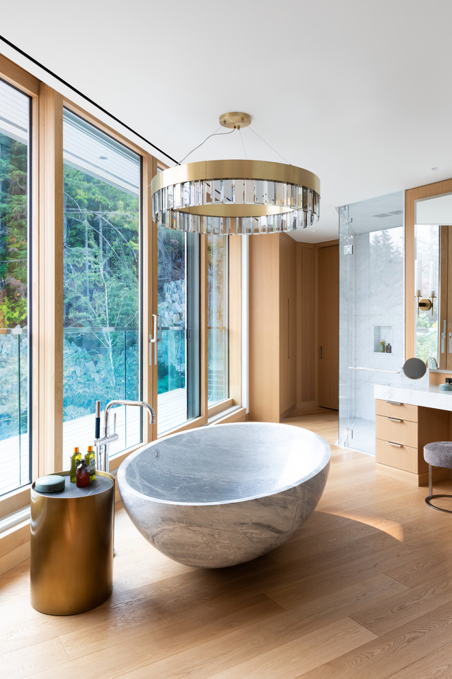 Design ideas for a contemporary ensuite bathroom in Other with flat-panel cabinets, light wood cabinets, a freestanding bath, a built-in shower, white tiles, light hardwood flooring, beige floors, a hinged door and white worktops.