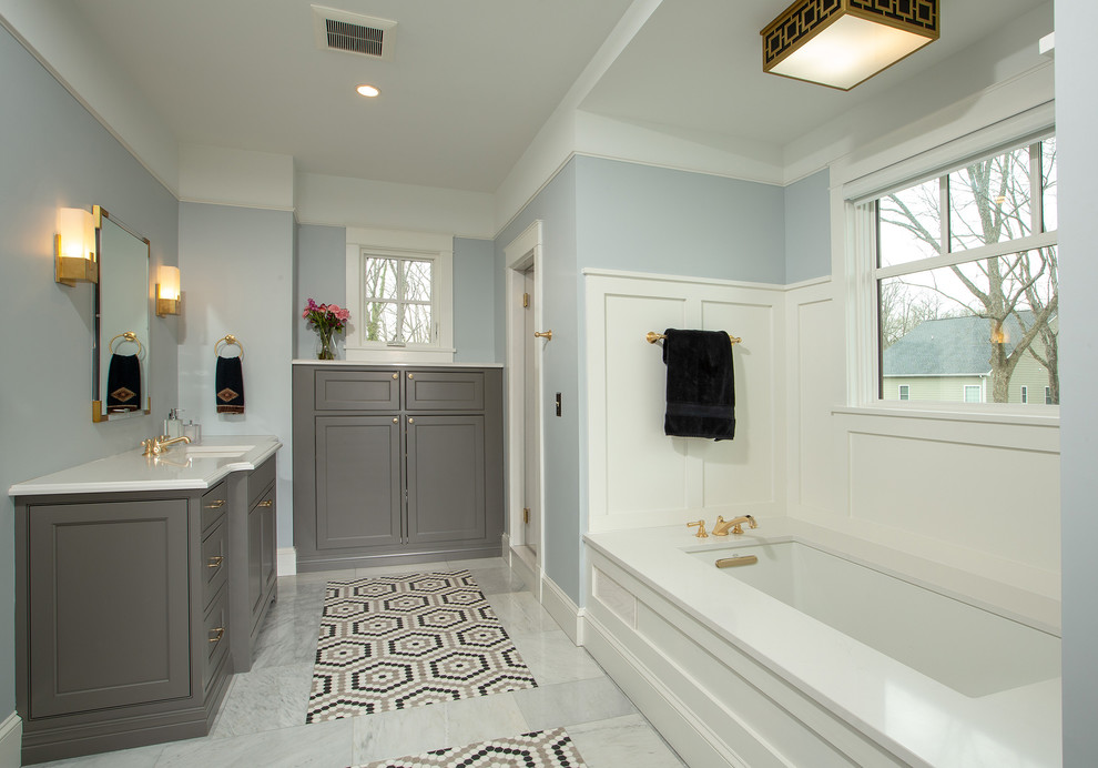 На фото: большая главная ванная комната в классическом стиле с фасадами с декоративным кантом, серыми фасадами, полновстраиваемой ванной, синими стенами, полом из мозаичной плитки, врезной раковиной, столешницей из искусственного кварца, белой столешницей, разноцветным полом и окном с