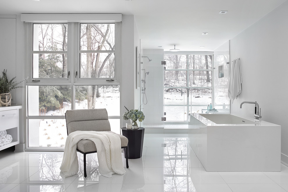 Cette photo montre une douche en alcôve tendance avec un placard à porte plane, des portes de placard blanches, une baignoire indépendante, un carrelage blanc, un mur blanc, un sol blanc et une cabine de douche à porte battante.