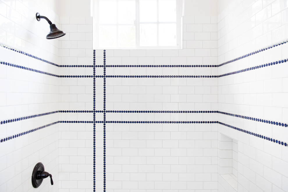 Photo of a medium sized traditional shower room bathroom in San Diego with shaker cabinets, blue cabinets, an alcove shower, a two-piece toilet, white tiles, metro tiles, white walls, dark hardwood flooring, a submerged sink, solid surface worktops, brown floors and white worktops.