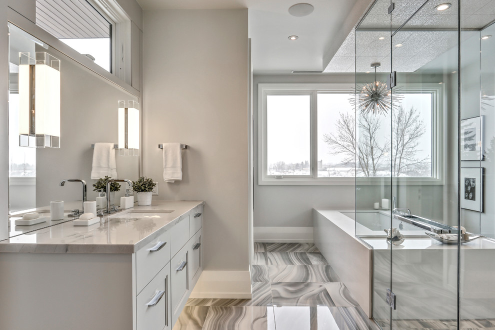 Design ideas for a large contemporary ensuite bathroom in Calgary with recessed-panel cabinets, white cabinets, a freestanding bath, a shower/bath combination, marble worktops and a hinged door.