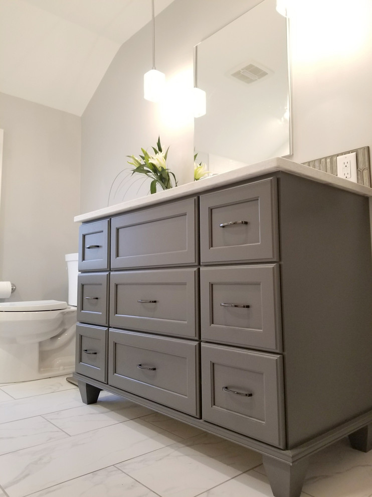 На фото: ванная комната среднего размера в стиле неоклассика (современная классика) с плоскими фасадами, серыми фасадами, ванной в нише, душем над ванной, раздельным унитазом, белой плиткой, керамической плиткой, серыми стенами, полом из керамогранита, врезной раковиной, столешницей из искусственного кварца, белым полом и душем с распашными дверями