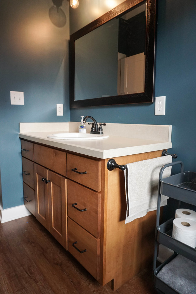 Esempio di una stanza da bagno classica di medie dimensioni con ante in stile shaker, ante in legno scuro, pareti blu, pavimento in legno massello medio, lavabo da incasso, top in superficie solida e pavimento marrone