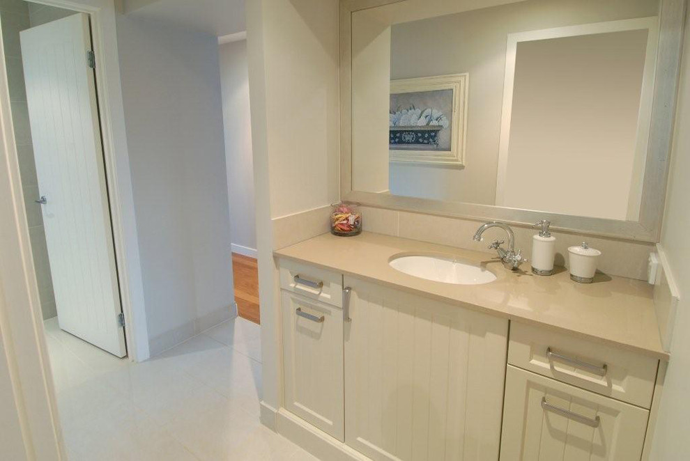 Cette photo montre une petite salle de bain chic avec un placard avec porte à panneau encastré et un lavabo encastré.