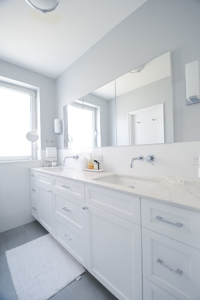Design ideas for a medium sized traditional ensuite bathroom in New York with shaker cabinets, white cabinets, a walk-in shower, a one-piece toilet, white tiles, white walls, cement flooring, a submerged sink, engineered stone worktops, grey floors, a hinged door and white worktops.
