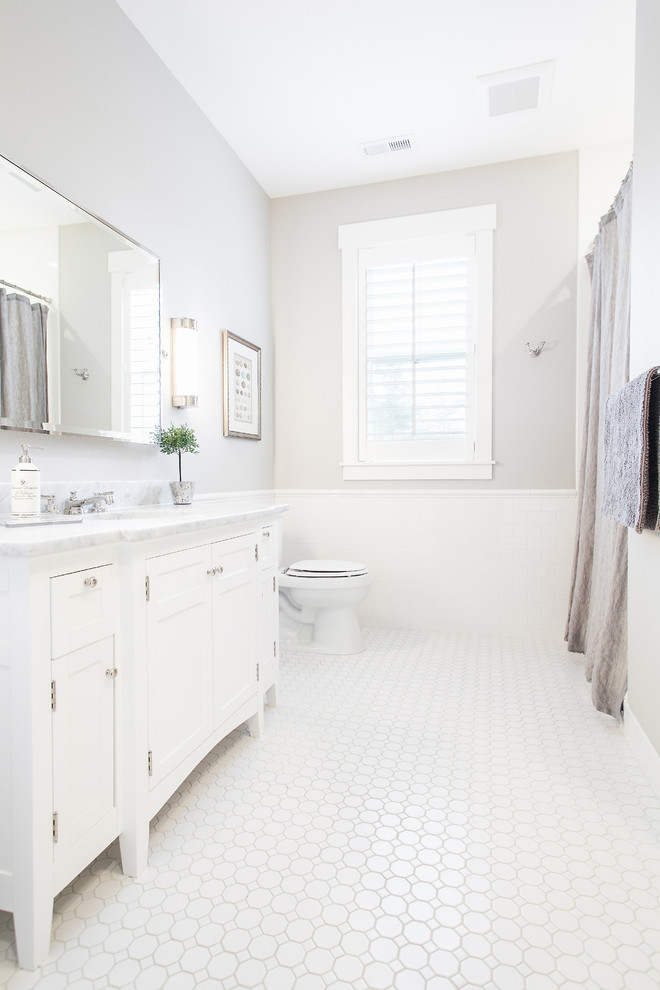 Cette image montre une douche en alcôve traditionnelle avec un lavabo encastré, un placard à porte shaker, des portes de placard blanches, un plan de toilette en marbre, WC séparés, un carrelage blanc et un carrelage métro.