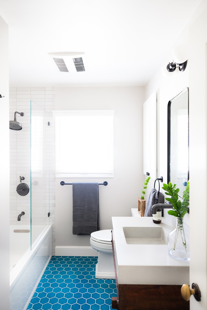 Пример оригинального дизайна: маленькая детская ванная комната в стиле неоклассика (современная классика) с коричневыми фасадами, душем над ванной, белой плиткой, белыми стенами, полом из керамической плитки, синим полом, открытым душем и белой столешницей для на участке и в саду