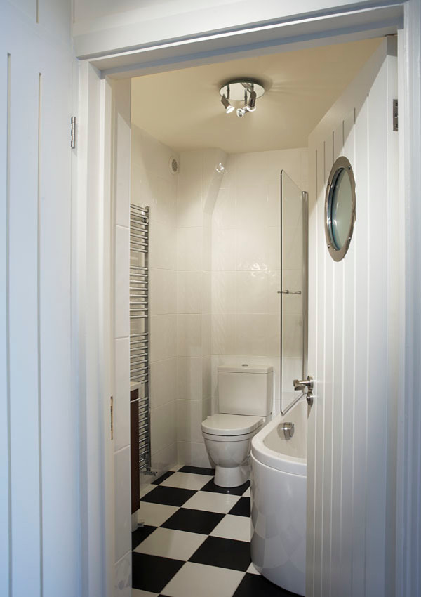 Large beach style ensuite bathroom in Oxfordshire with flat-panel cabinets, dark wood cabinets, a built-in shower, a one-piece toilet, black and white tiles, porcelain tiles, white walls, porcelain flooring, a built-in sink and tiled worktops.