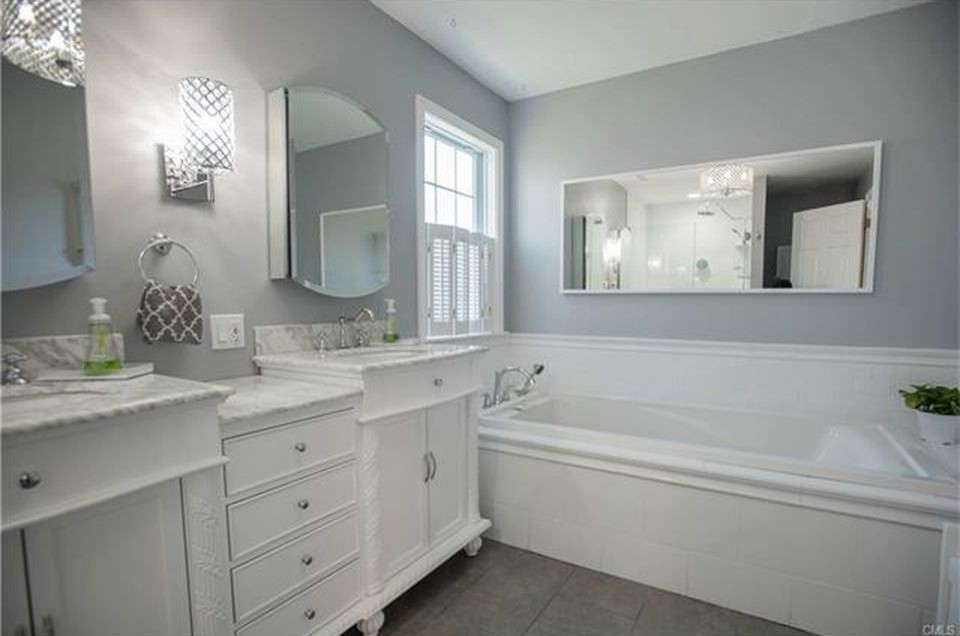 Design ideas for a medium sized traditional ensuite bathroom in Bridgeport with freestanding cabinets, white cabinets, a corner bath, white tiles, metro tiles, grey walls, ceramic flooring, a submerged sink, marble worktops, brown floors and grey worktops.